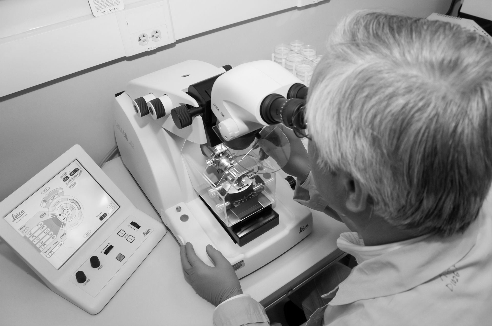 Laboratory technician using a Leica microscope for forensic analysis, emphasizing precision in criminal defense investigations.